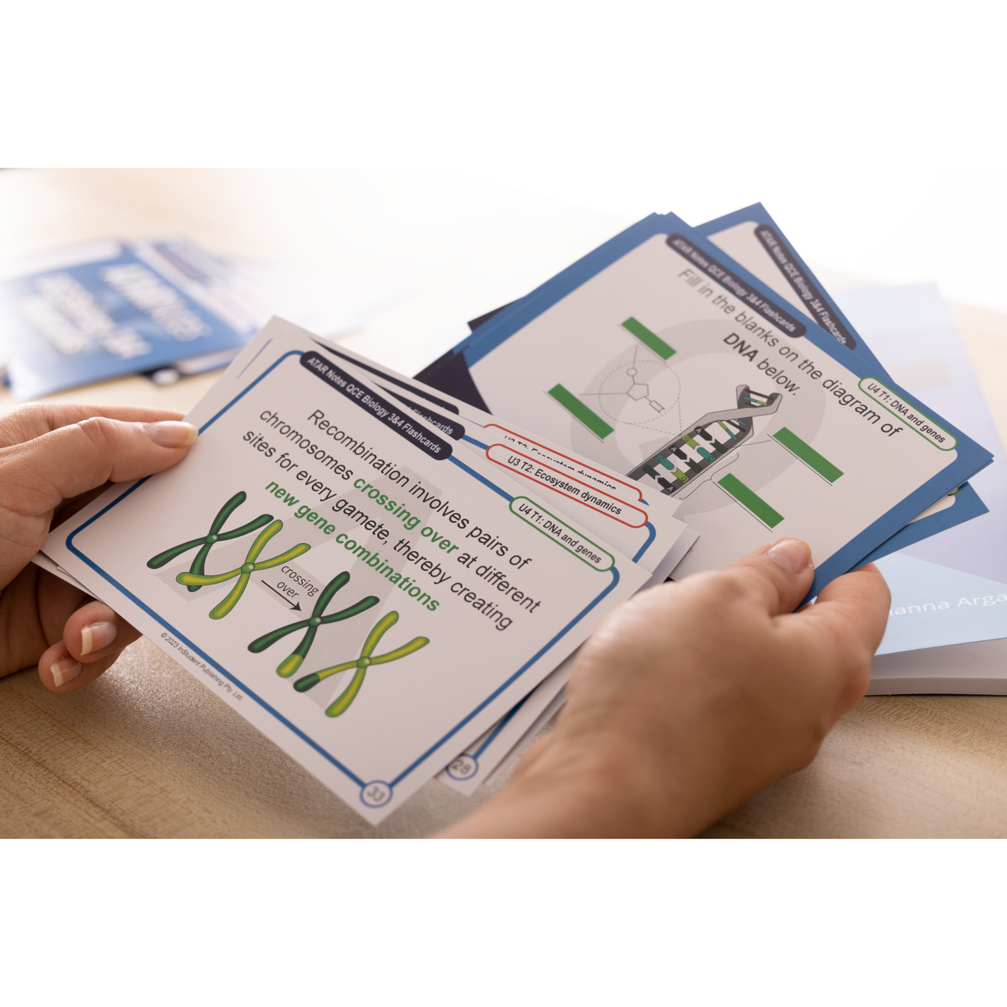 Othello Flashcards by ATAR Notes, white with blue accents, depicting biology diagrams, held in hands.